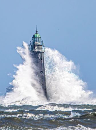 photo of wave crashing against a lighthouse