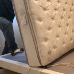 Image of a mattress standing vertically on bed foundation with foot kicking its bottom